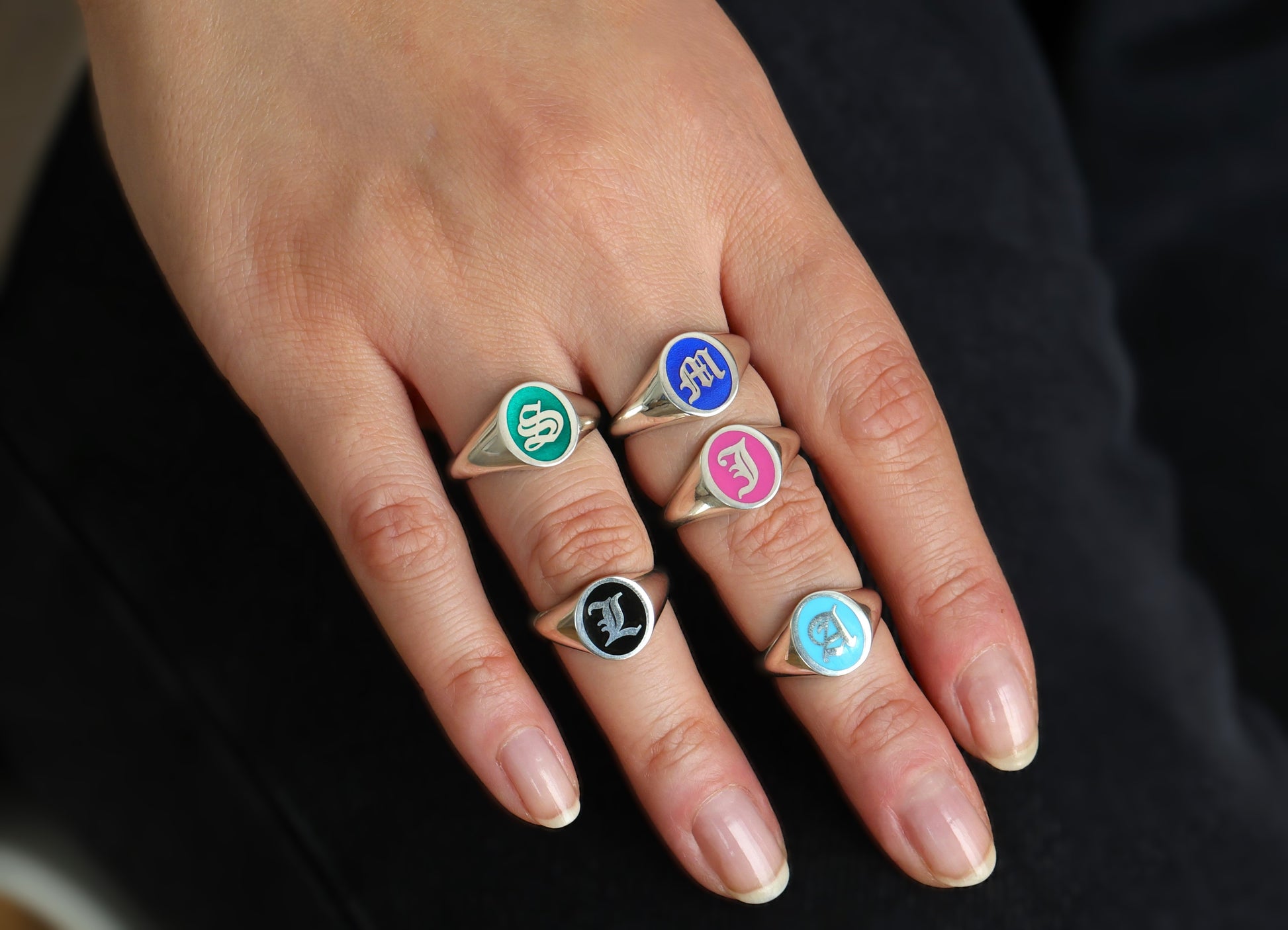 Custom initial signet rings showing navy blue, baby blue, pink, and green enamel options.