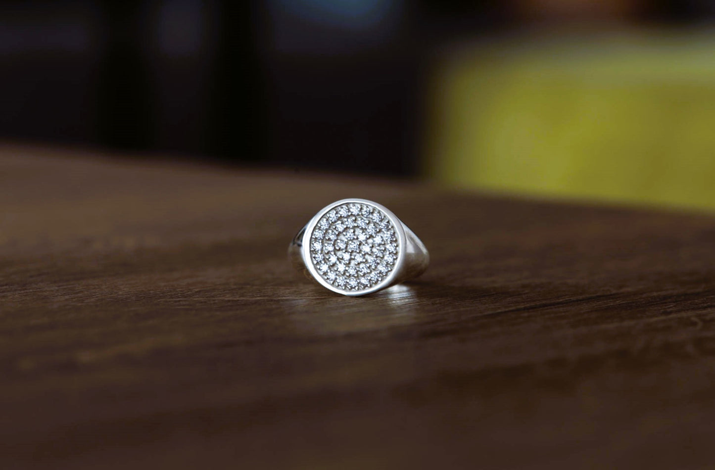 Silver ring with pave diamond design on a wooden surface