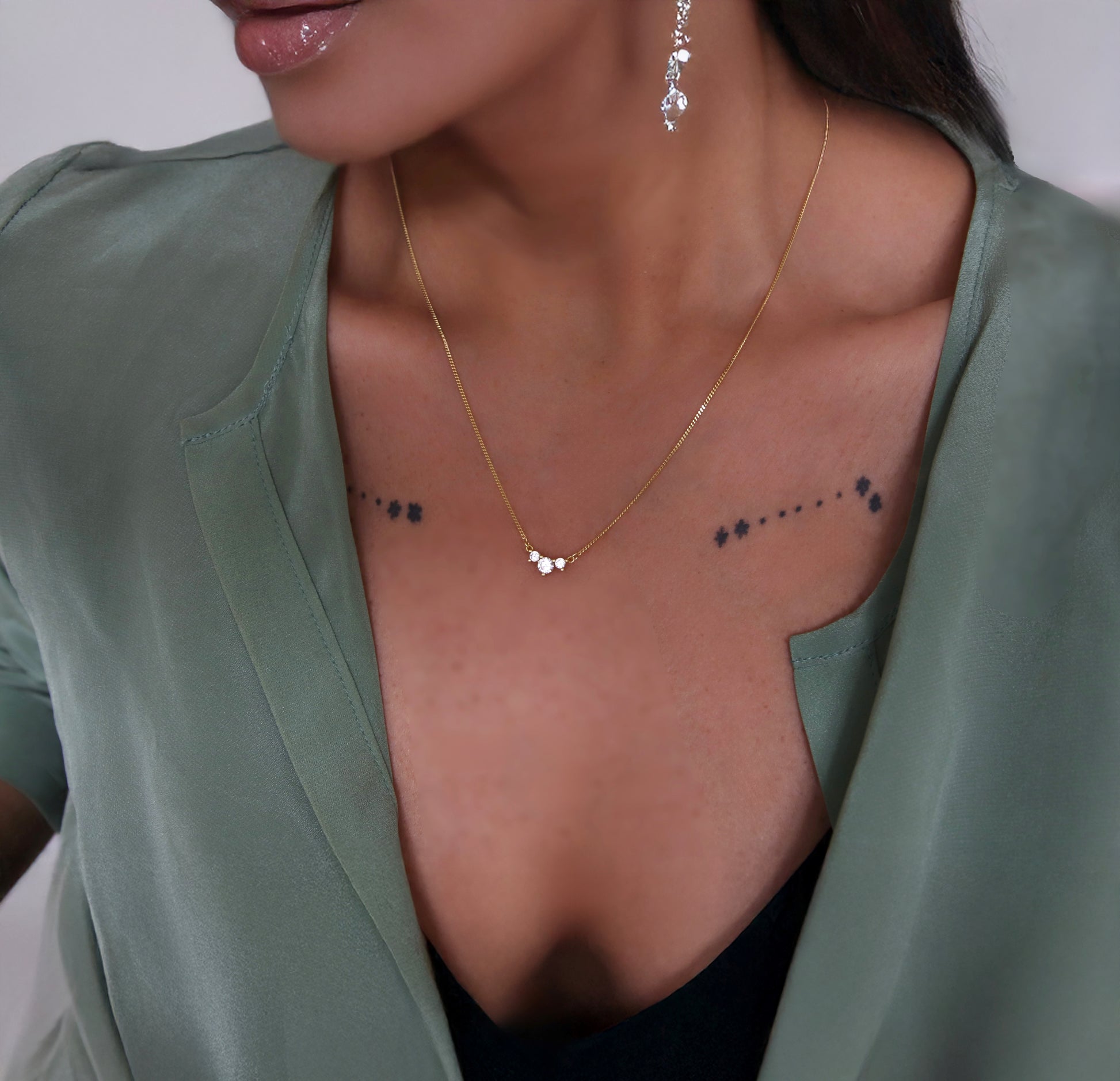 Close-up of a woman wearing a delicate gold necklace with 3 cz stones.