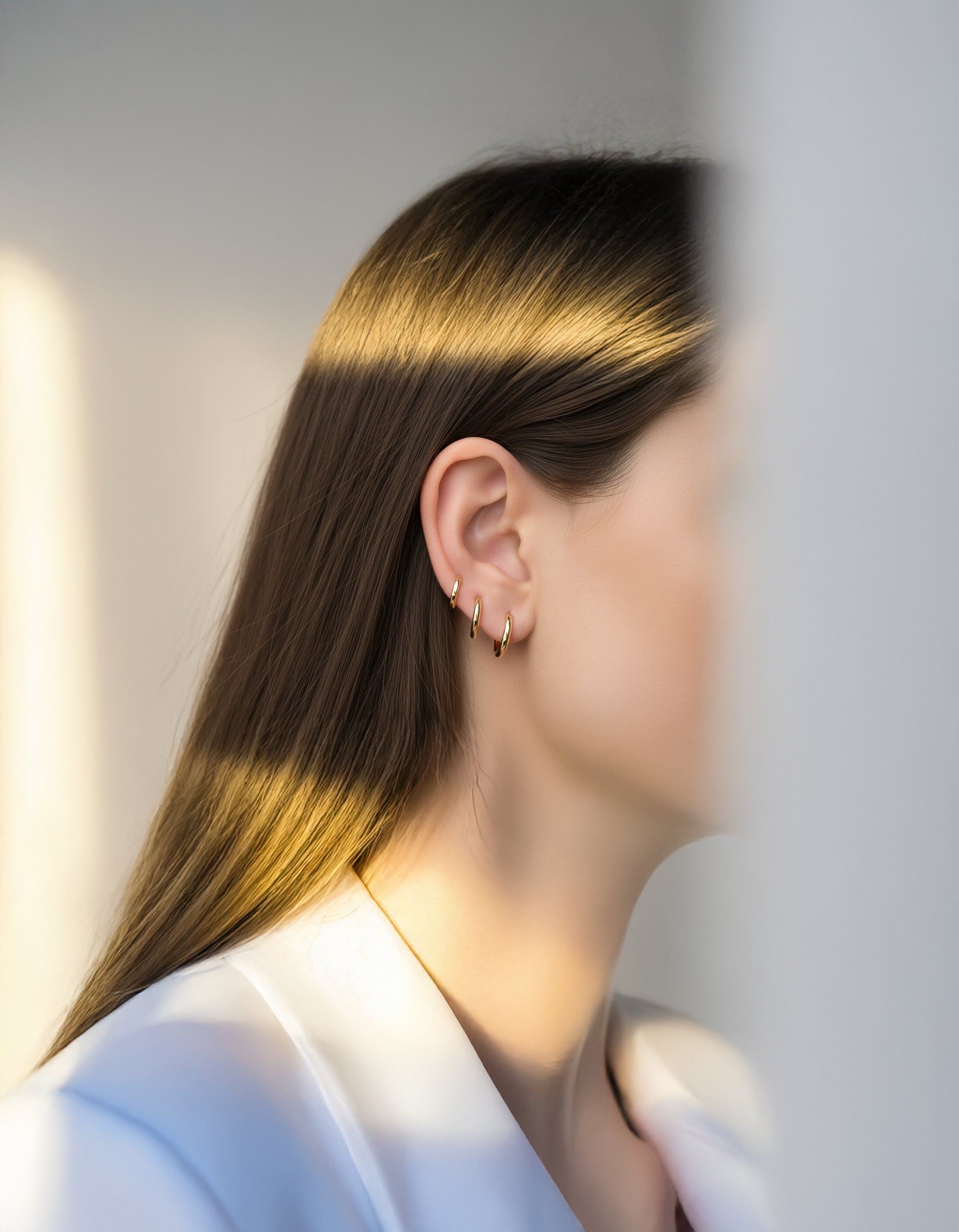 Model wearing minimalist huggie hoop earrings with a neutral background