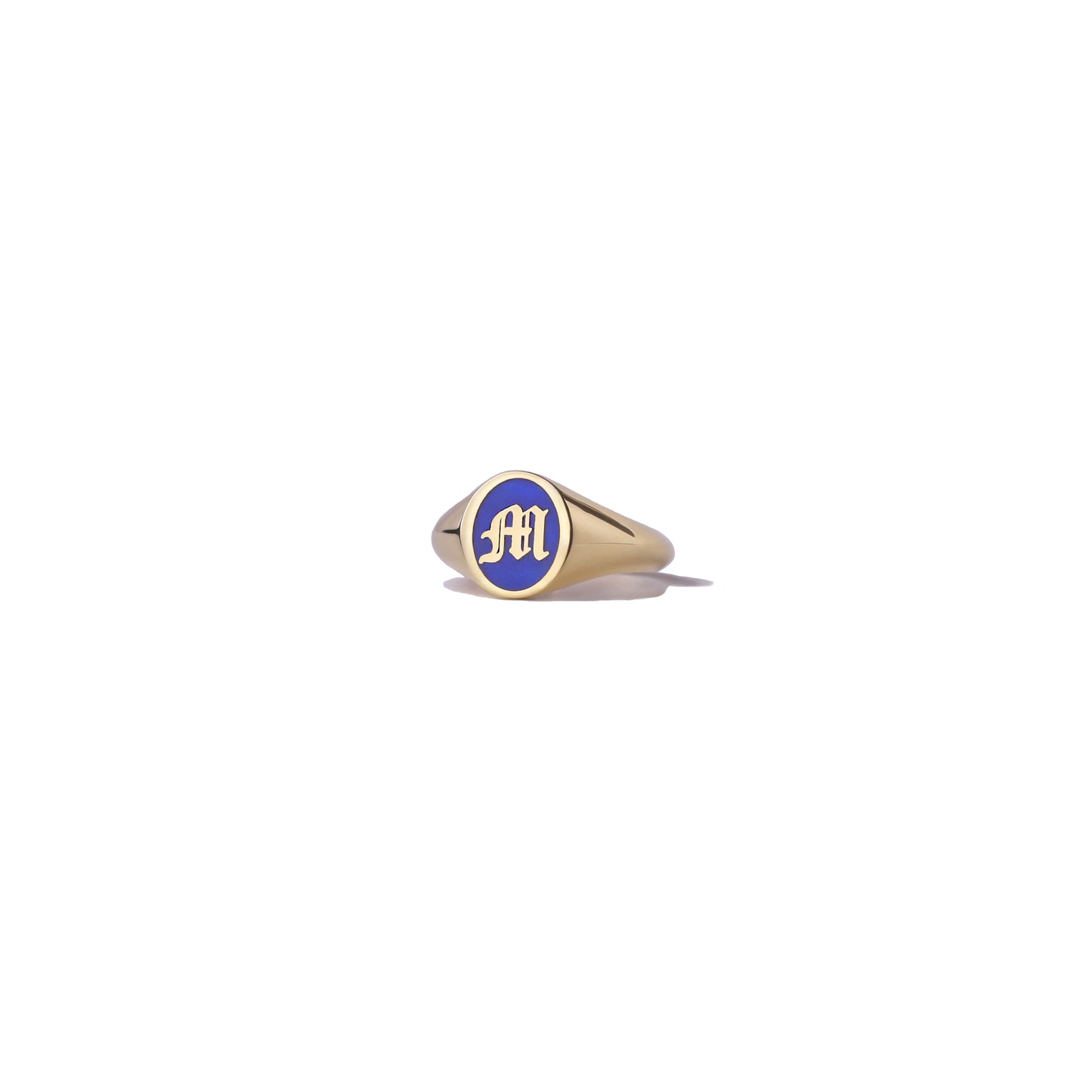 Gold initial signet ring with blue enamel on a white background