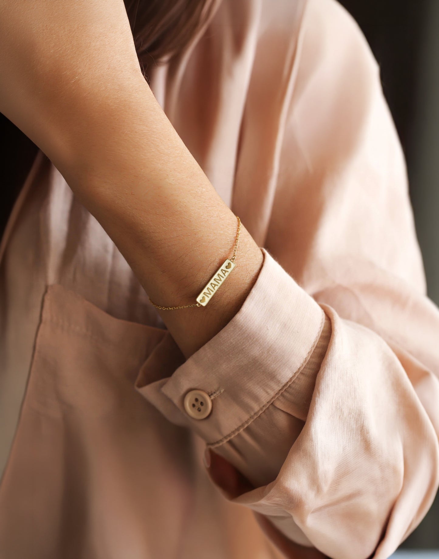 14k solid gold mama bracelet worn elegantly on a woman's wrist.