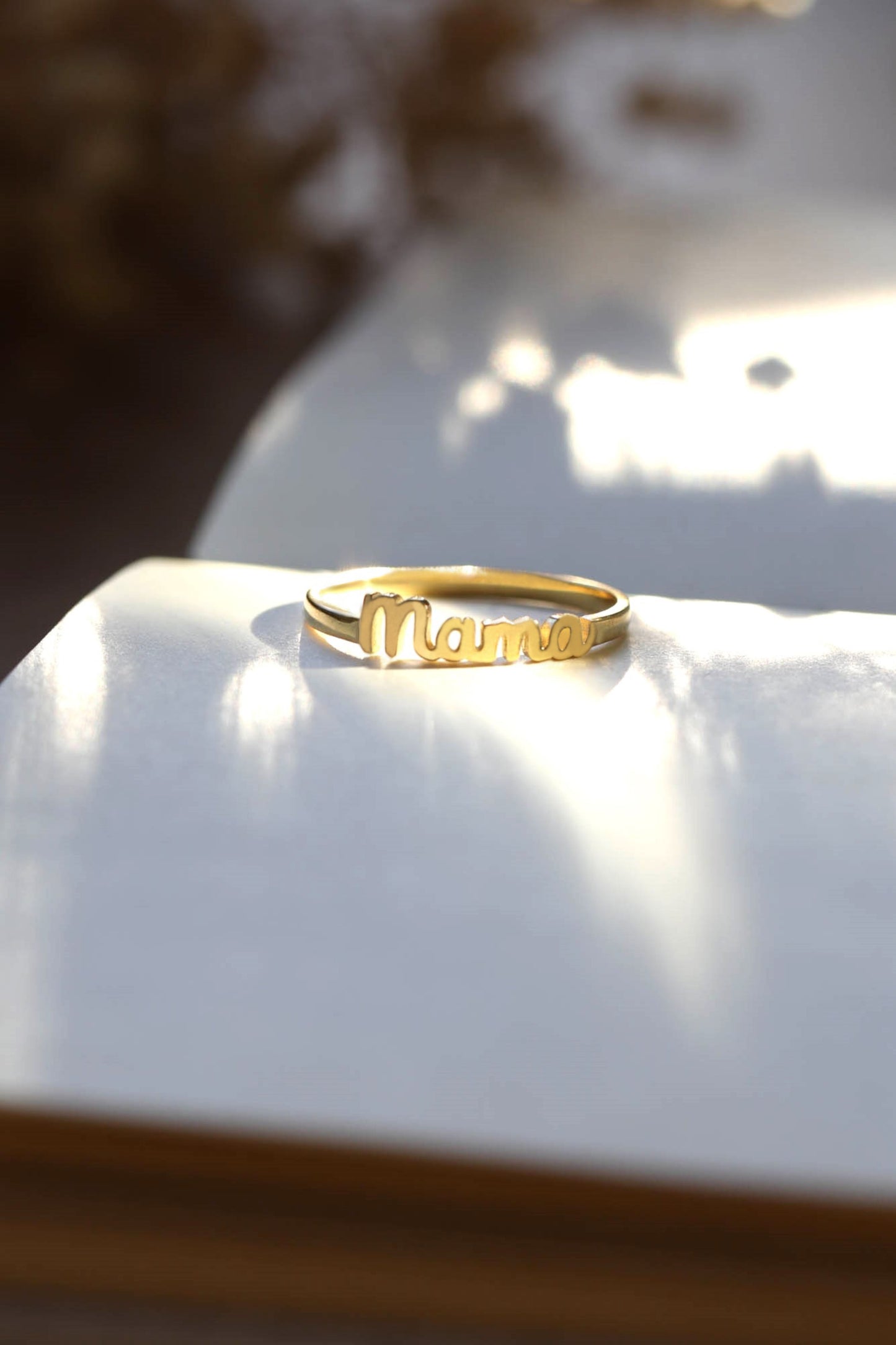 Gold ring with 'Mama' on a white surface