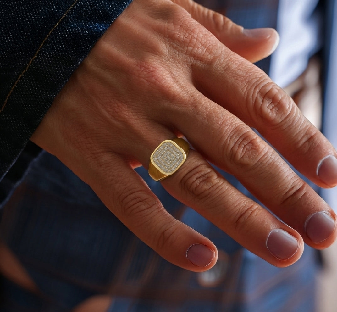 Men's gold, square, paved signet ring worn on hand.