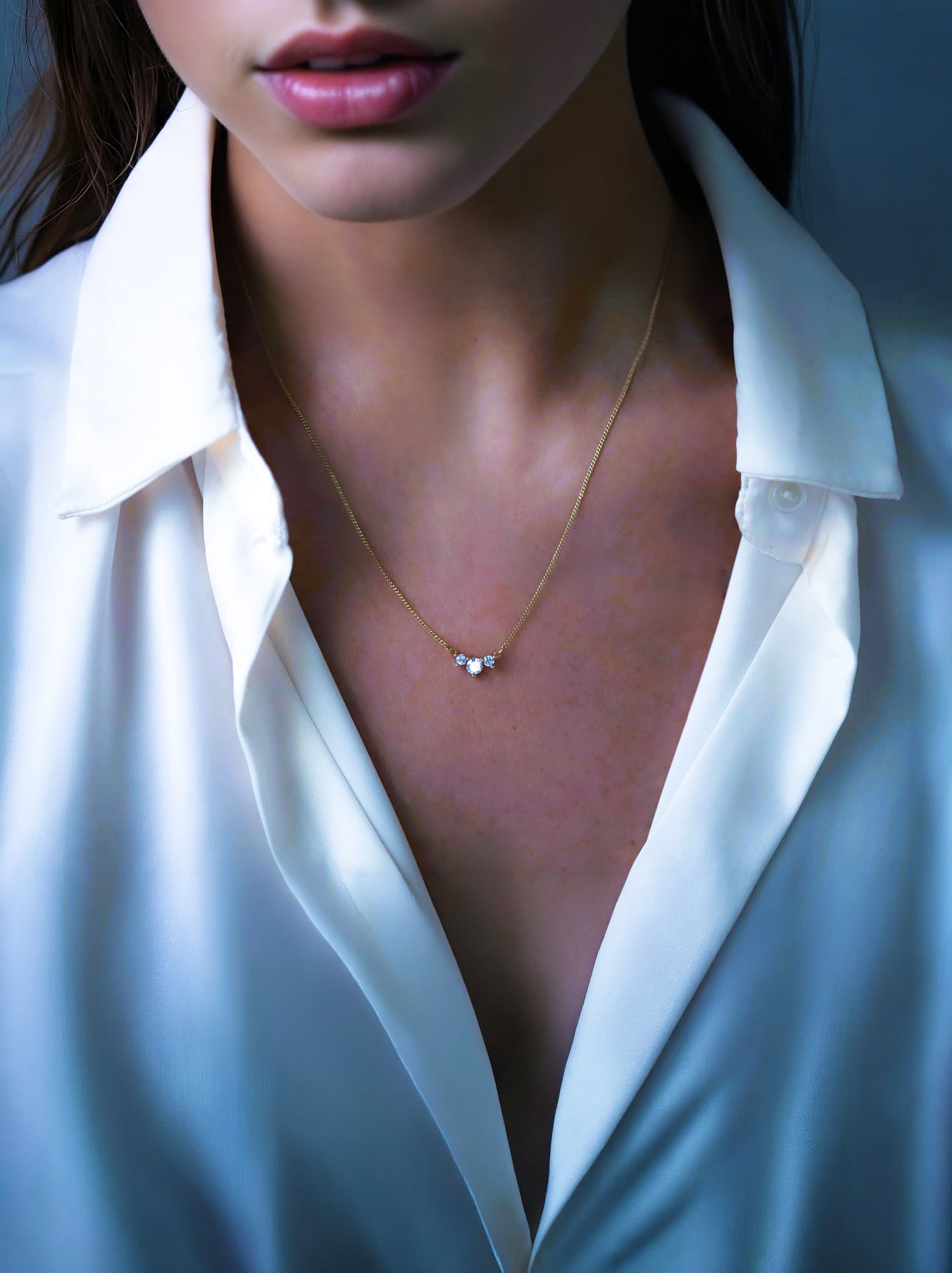 Modern woman wearing the dainty 3 stone cz necklace with a crisp white silk shirt.