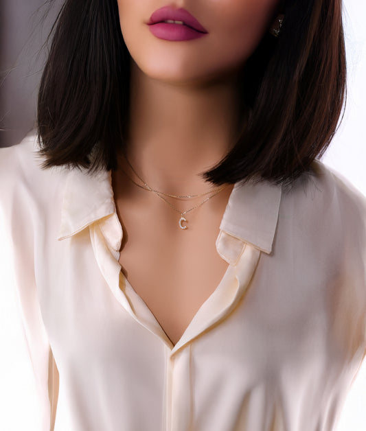 Solid 14k yellow gold necklace featuring a diamond paved letter c initial pendant worn by a model.