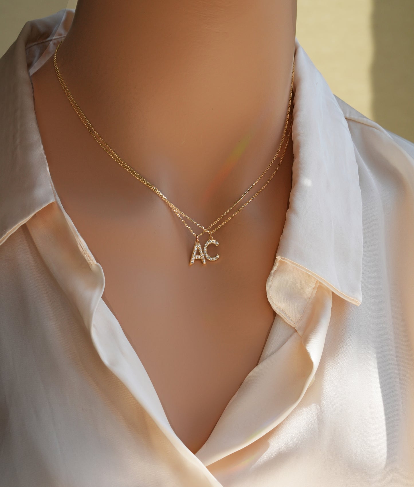 Solid gold letter necklace with diamond paved A and C initials worn on the neck.