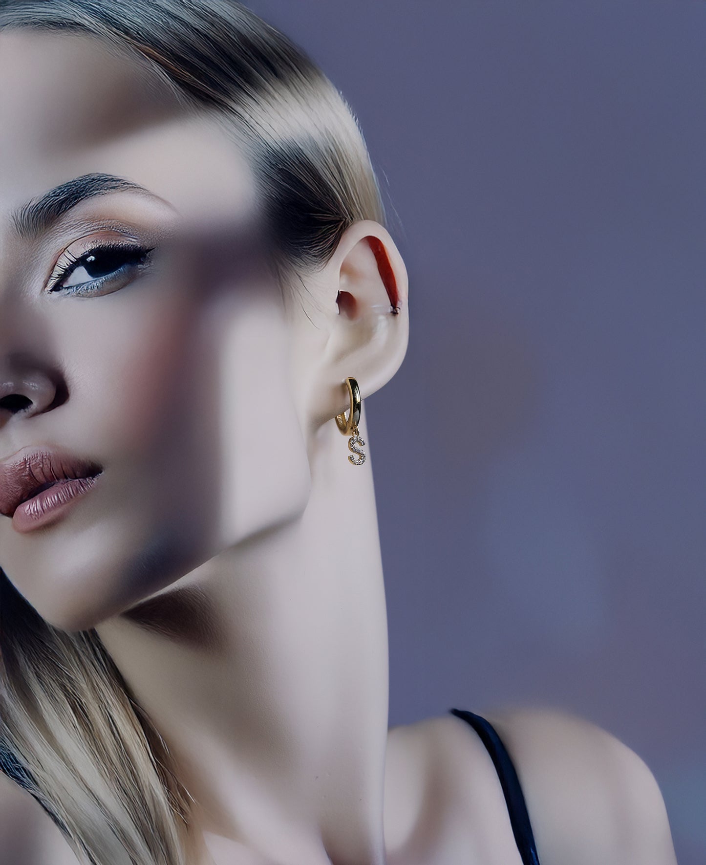 Close-up of a woman wearing gold solid gold initial earrings 