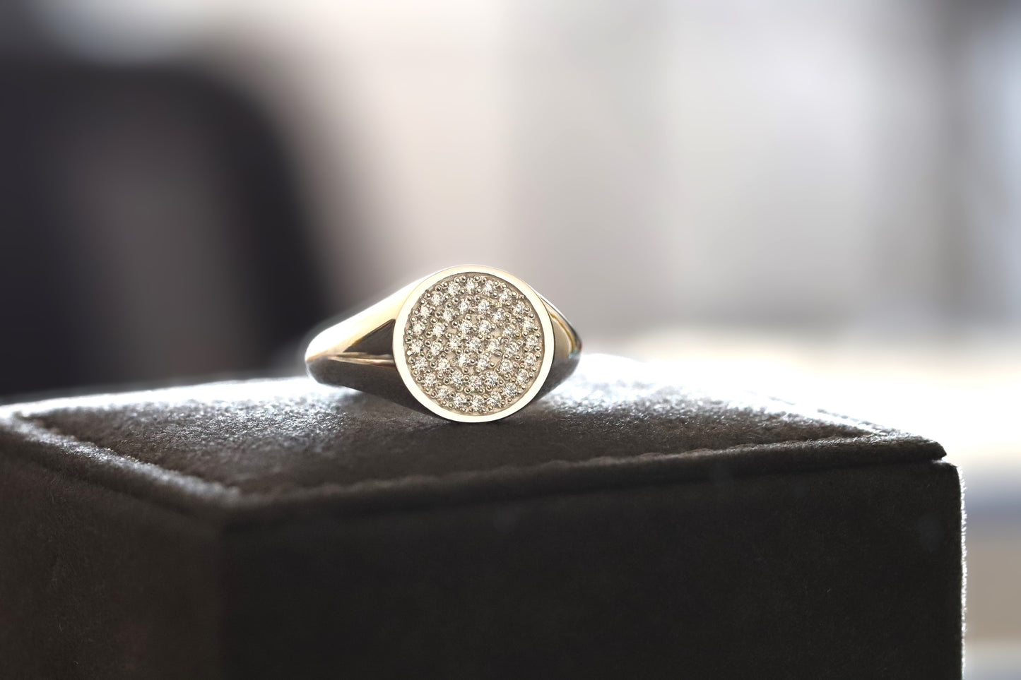 signet ring with diamonds on a black box against a blurred background