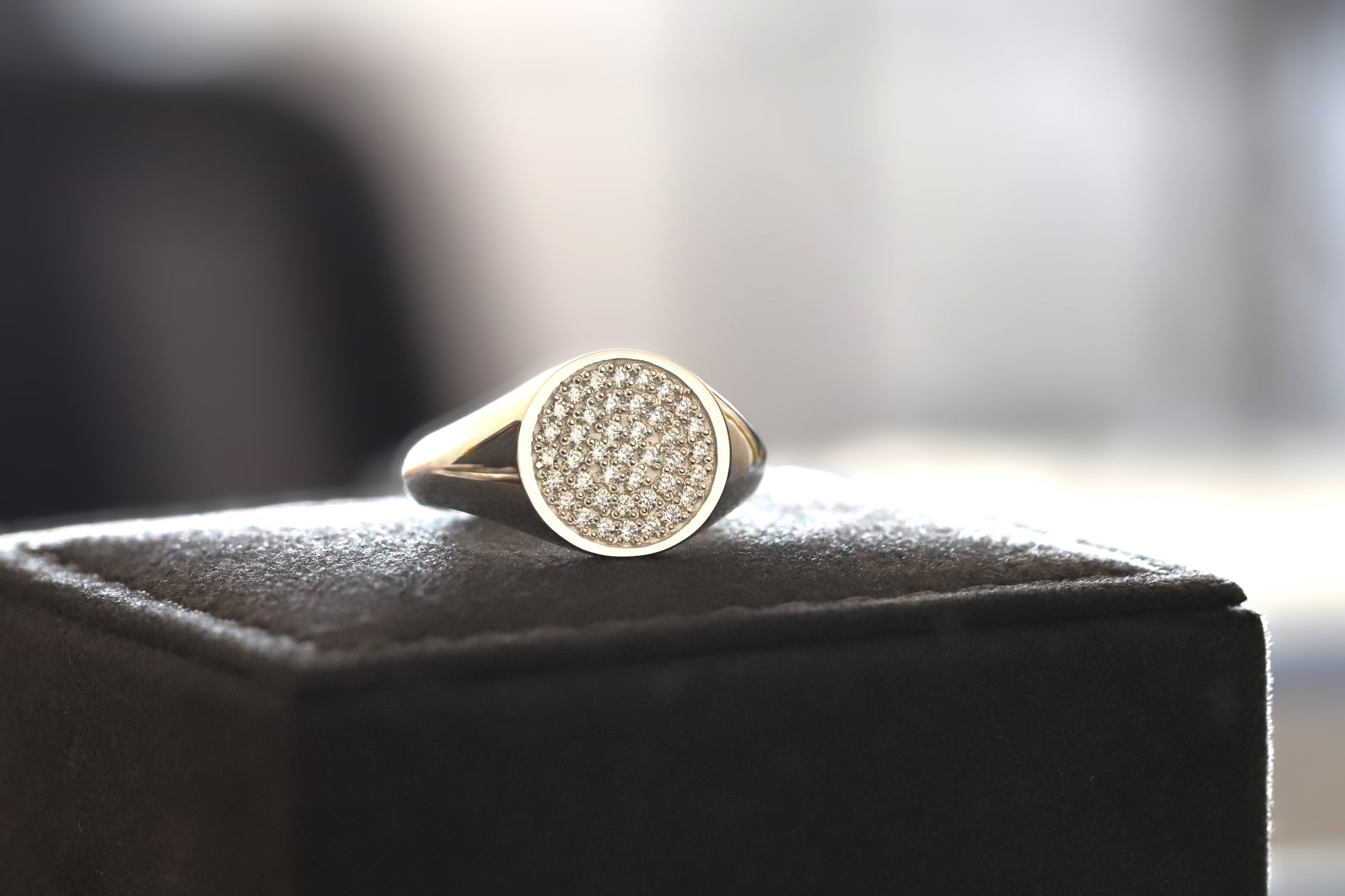 signet ring with diamonds on a black box against a blurred background