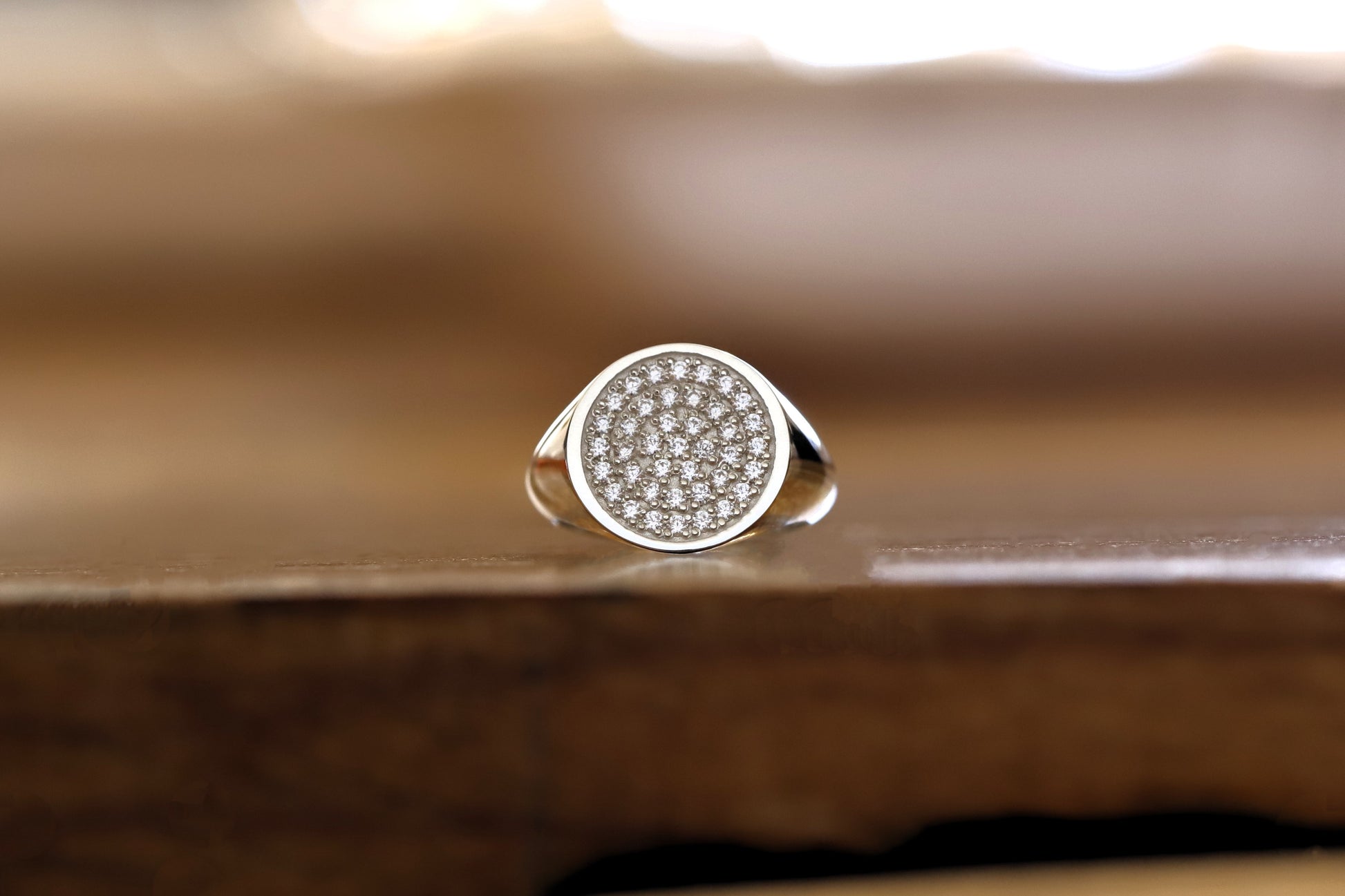 Silver paved signet ring with cz stones on a wooden surface