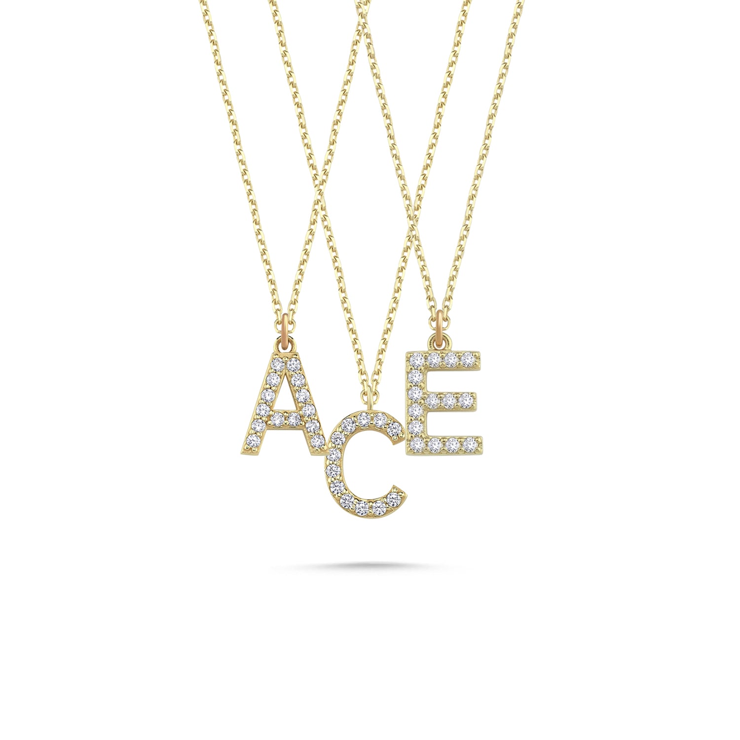 Three solid gold diamond paved initial necklaces featuring the letters A, C, and E.