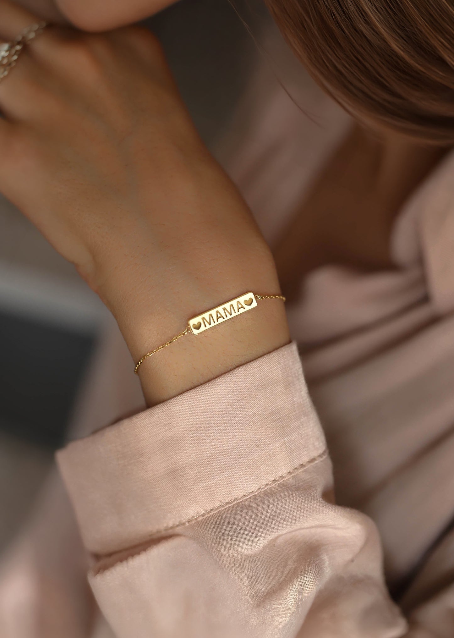 14k solid gold mama bracelet worn elegantly on a woman's wrist.