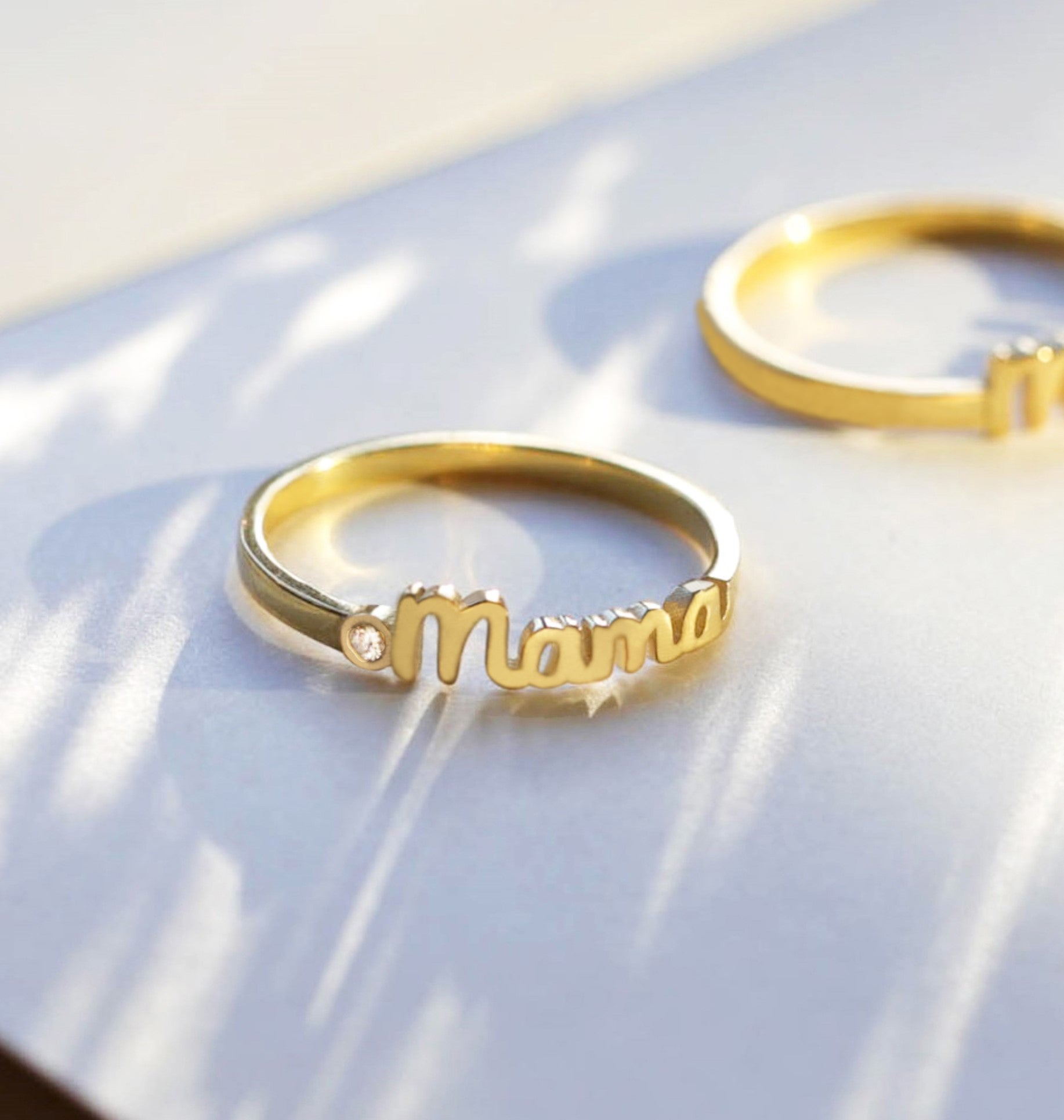Gold ring with 'mama' engraving on a white surface