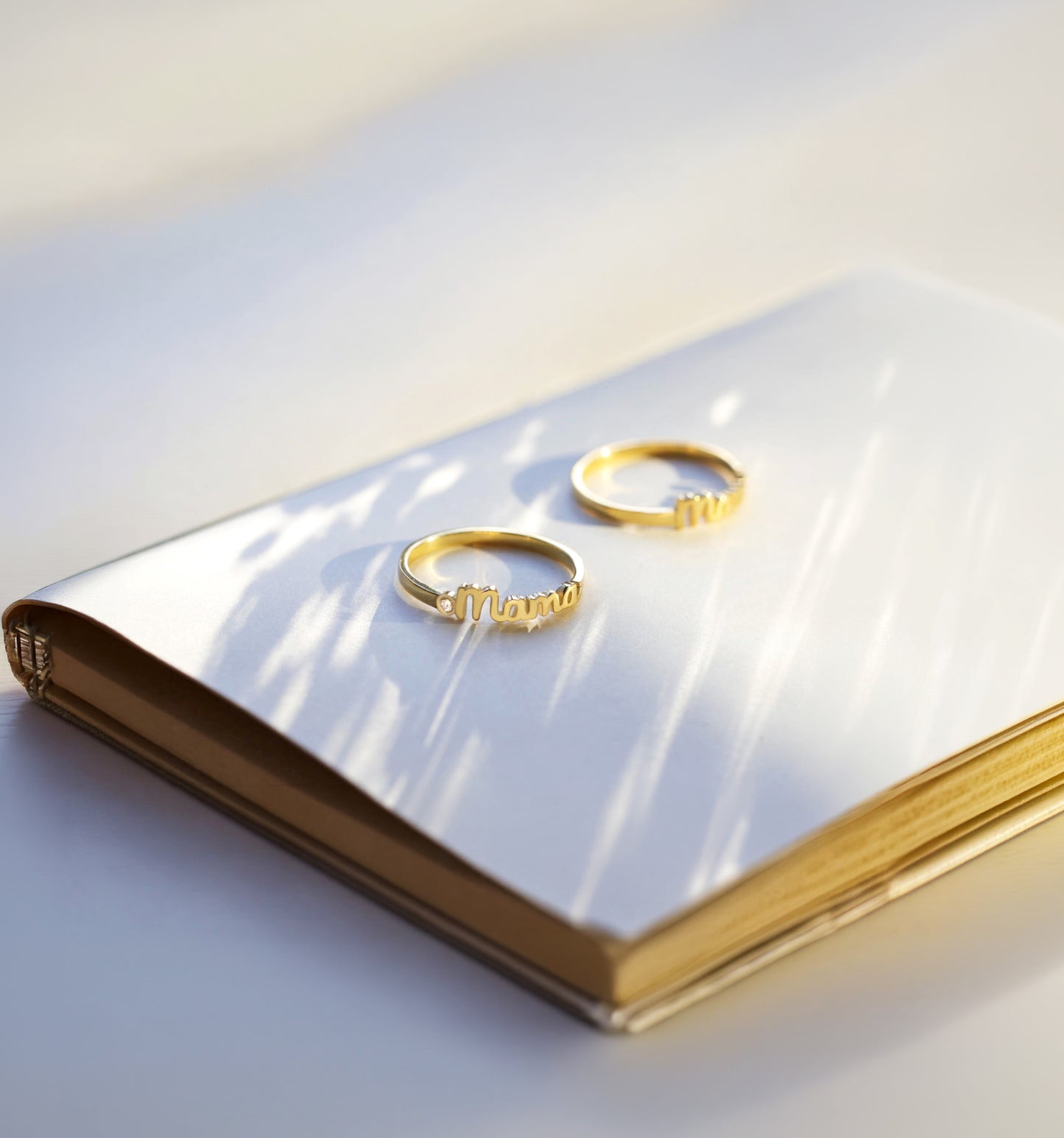 Two gold mama rings on a white surface with a soft light background