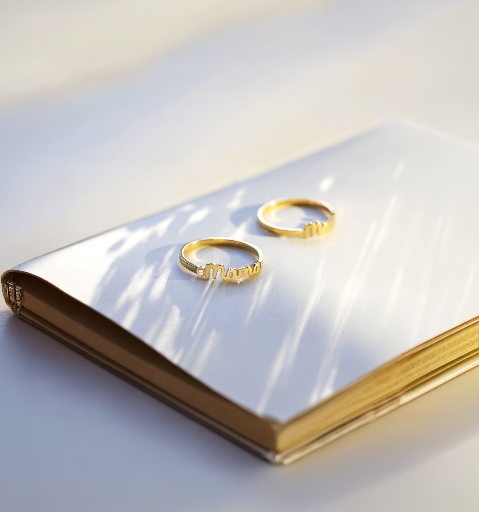 Two gold mama rings on a white surface with a soft light background