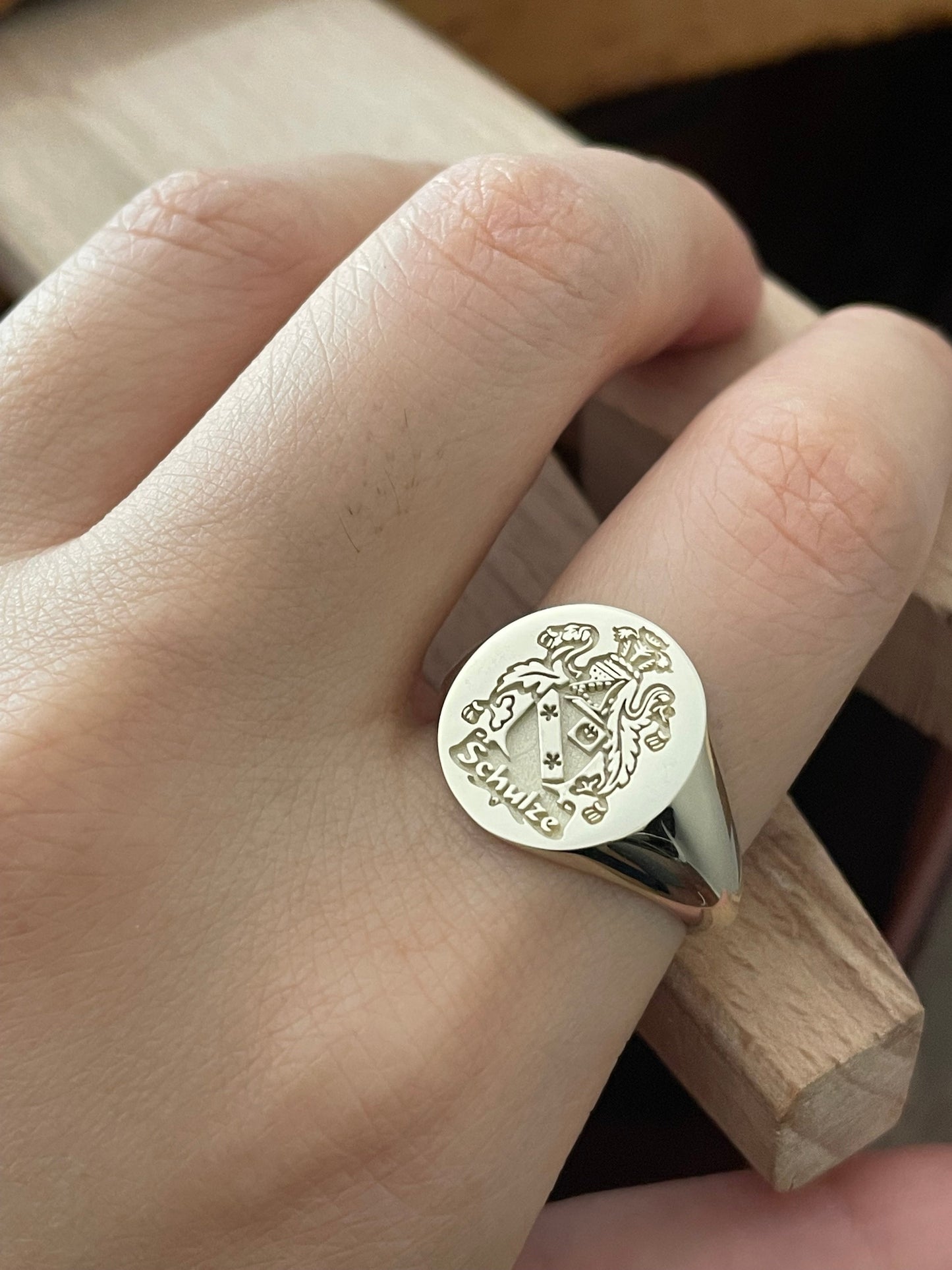 close-up of a hand wering a gold signet ring engraved with a family crest design