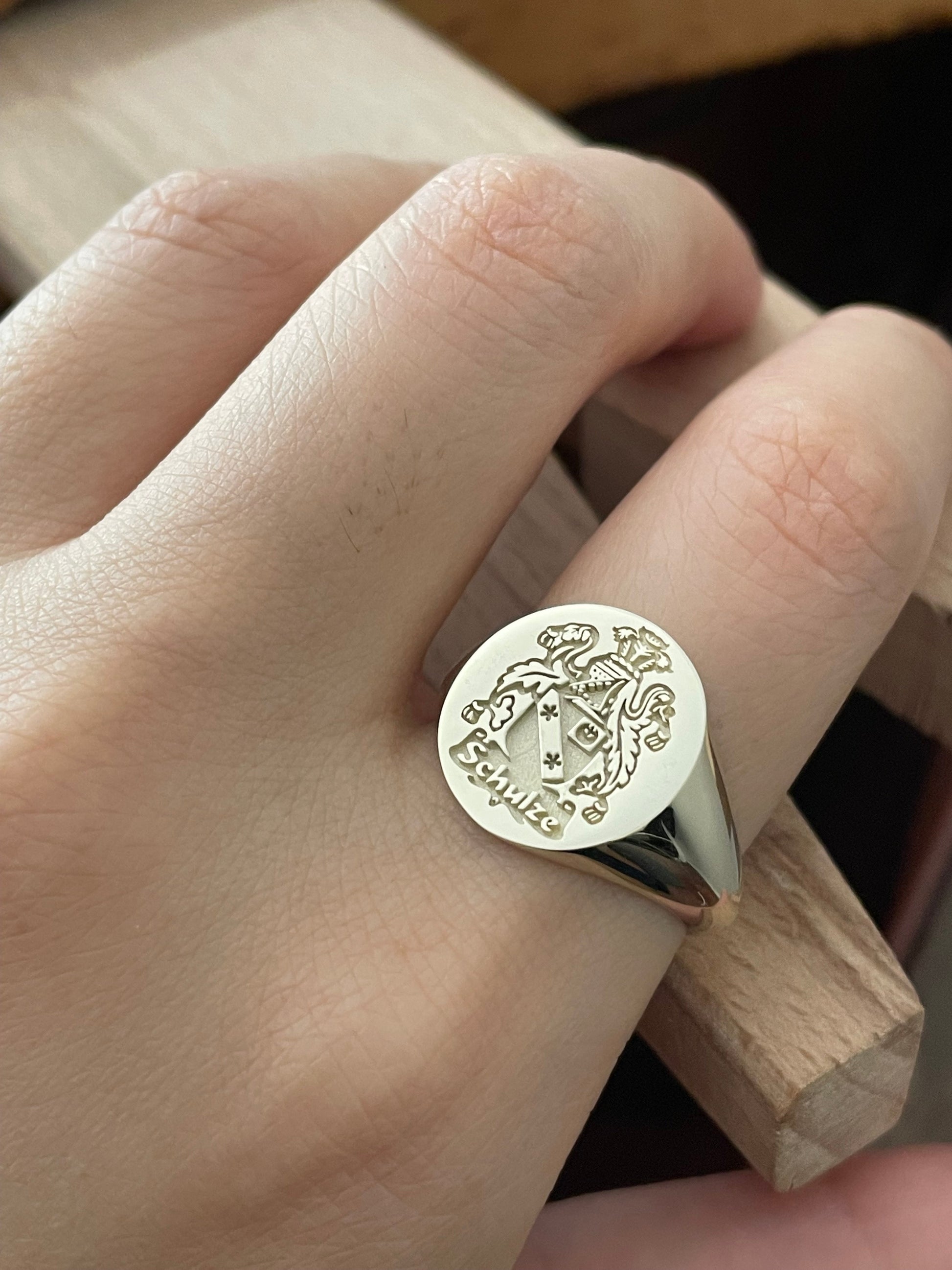 close-up of a hand wering a gold signet ring engraved with a family crest design
